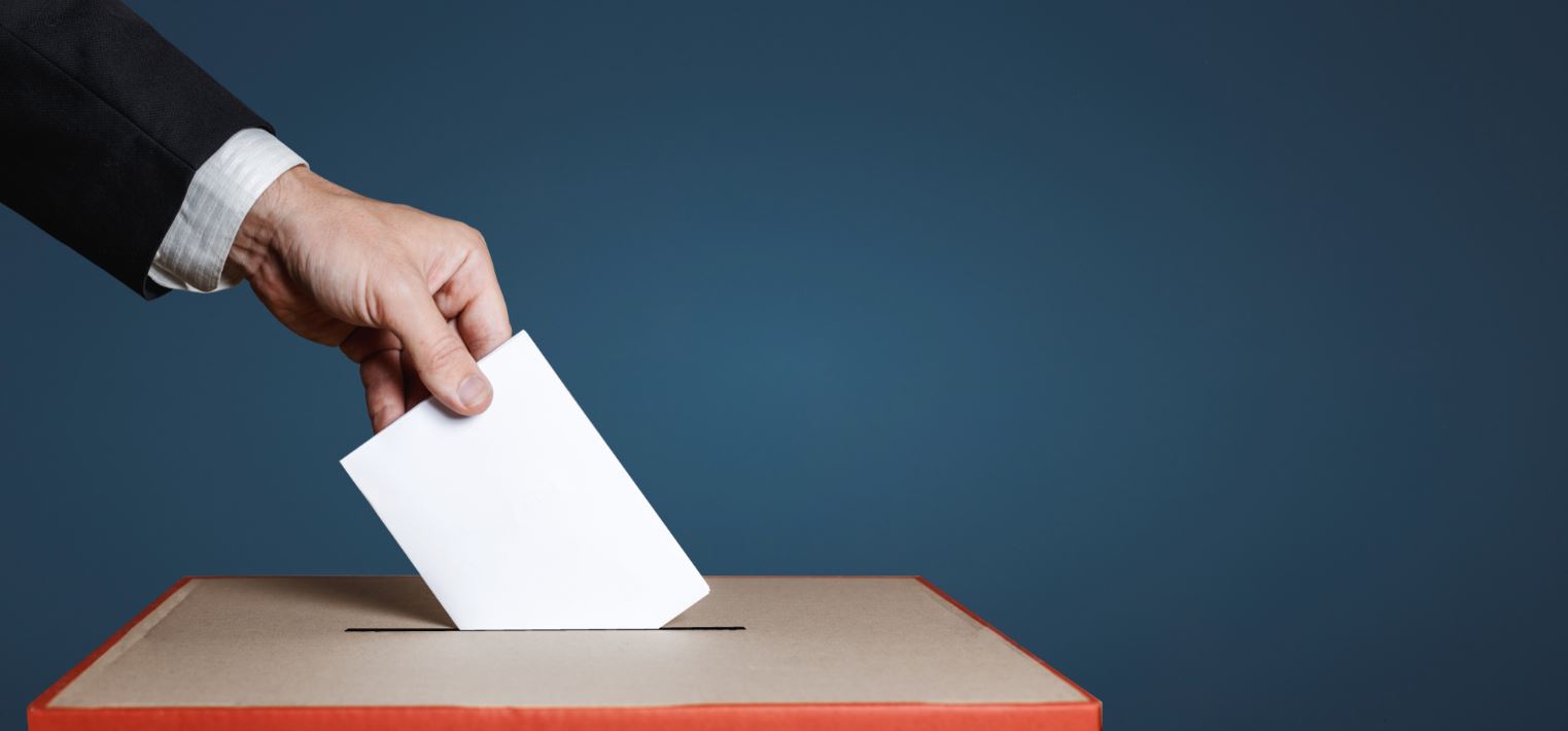 hand casting a ballot in a ballot box